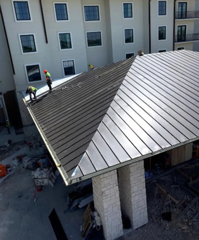 Crew installing standing seam metal roof panels on a commercial project in Clifton